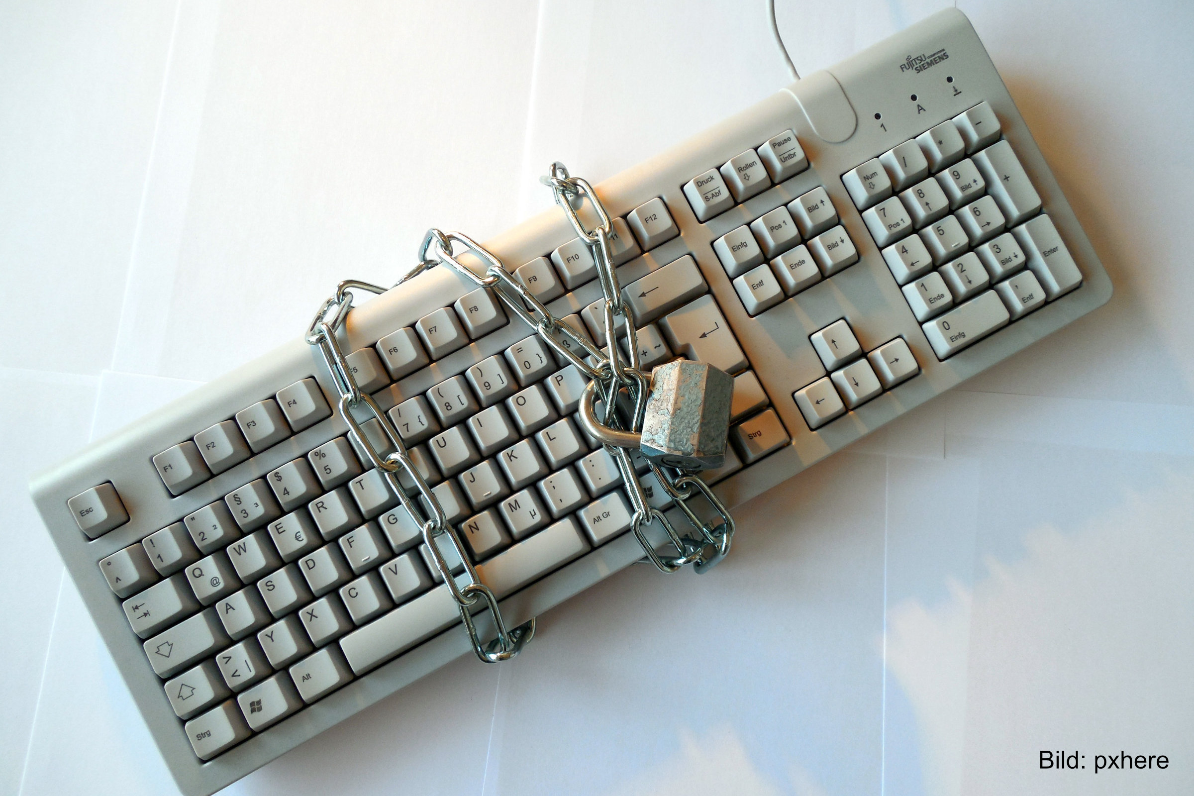 Eine Tastatur ist mit einer Kette und einem Schloss gesichert. Symbolbild für IT-Sicherheit und Digitalisierung.